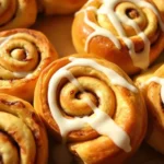 Freshly baked crescent roll cinnamon rolls drizzled with vanilla glaze on a white plate